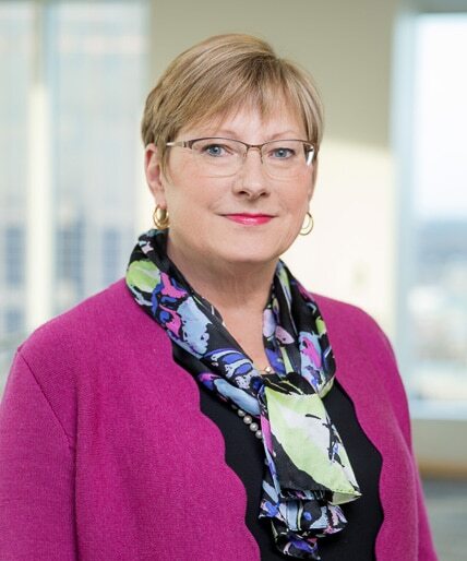 Susie Gibbons, Counsel at Poyner Spruill LLP seen posing for a photo in dark pink and black combination outfit